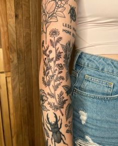 a woman's arm with tattoos and flowers on it