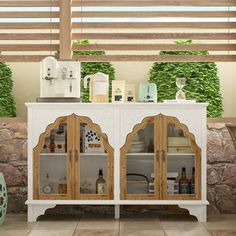 a white and wood cabinet with glass doors on the front, sitting under a pergolated roof