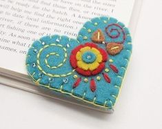 a book with a heart shaped brooch sitting on top of it