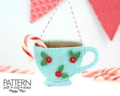 a tea cup ornament with candy canes hanging from it