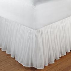 a bed with a white ruffled bedskirt