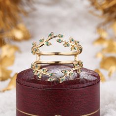 a gold ring sitting on top of a wooden box with green stones in the middle