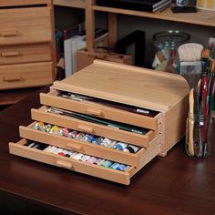 a wooden desk with several drawers and paintbrushes in them on top of it