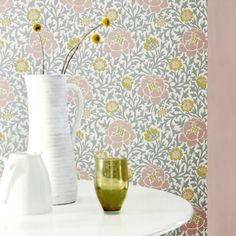 two vases with yellow flowers are on a table next to a wallpapered background