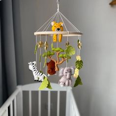 a baby crib with an animal mobile hanging from it's side