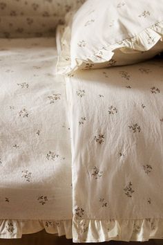 an unmade bed with white linens and flowered bedspread on it