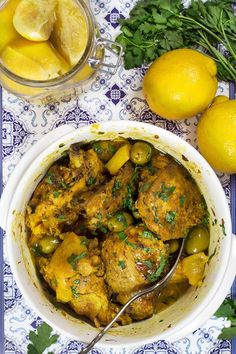 a bowl filled with chicken and vegetables next to lemons