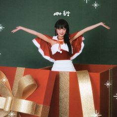 a woman standing in front of a christmas present with her arms spread out and hands outstretched