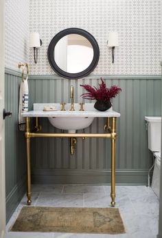 a white sink sitting under a mirror in a bathroom next to a wall mounted toilet