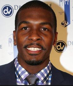 a close up of a person wearing a suit and tie with a smile on his face