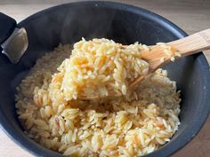 a wooden spoon stirring rice in a black bowl