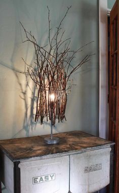 a table with two drawers and some branches on it in front of a wall mounted candle holder