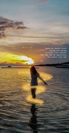 a woman standing in the water at sunset with her arms spread out, holding a paddle