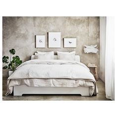 a bed with white linens and two framed pictures on the wall above it in a bedroom