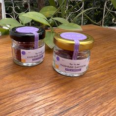 two jars of jam sitting on top of a wooden table