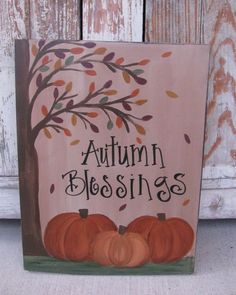 a wooden sign that says autumn blessings with pumpkins in front of a tree