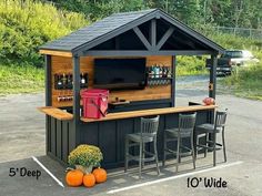 an outdoor bar with stools and a television on top in a parking lot next to some pumpkins