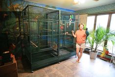 a woman standing in front of a large bird cage