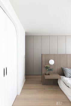 a bedroom with white walls and wood flooring is pictured in this image, there are two nightstands on either side of the bed