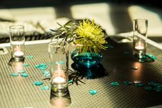 a table topped with candles and flowers on top of a metal table covered in confetti