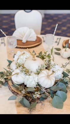 a table with white pumpkins, greenery and napkins on top of it