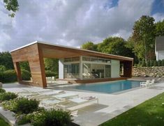 a house with a swimming pool in the middle of some grass and trees around it