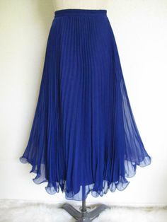 This is a lovely, swirly crystal pleated evening skirt in silk-like polyester chiffon. Marked a size 12. Please note that vintage tends to run small. The waist measures 27" with some stretch available. No brand tag - just a size/fiber content tag, and "Union Made in America." Rich royal purple. The purple is more blue than reddish. Elasticized waistband. Invisible back zip, with hook and eye. Maxi length. The hem is wonderful - it has a filament encased in the hem, which gives the hem a swirly, Vintage Formal Skirt For Summer, Vintage Evening Lined Skirt, Vintage Blue Pleated Bottoms, Elegant Blue Chiffon Skirt, Vintage Evening Pleated Skirt, Vintage Pleated Skirt For Evening, Vintage Skirted Party Skirt, Vintage Skirted Bottoms For Party, Vintage Formal Full Skirt Bottoms