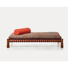 a bench with an orange pillow on top of it and a blanket on the bottom