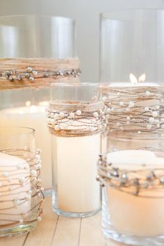 candles are lined up in glass containers on the table