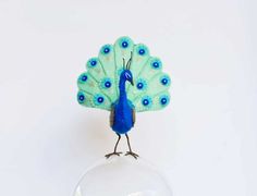 a blue and green bird sitting on top of a glass ball in front of a white wall