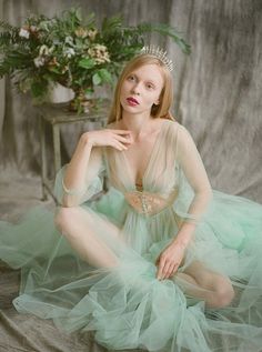 a woman wearing a tiara sitting on a bed in front of a flower arrangement