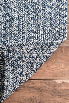 a blue and white rug on top of a wooden floor with wood planks in the background