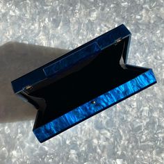 This acrylic party box clutch features a hand swirled acrylic exterior in a mesmerizing blue. Push open the matching acrylic top clasp and inside you will find a black lined interior. Comes with optional gold-toned crossbody chain to carry as a shoulder bag or you can add one of our acrylic chains for even more style. Fits an iPhone Plus with case. ▪️Length: 7.25", Height: 3.75", Depth: 1.75" ▪️Materials: acrylic, plated metals, cotton/polyester lining. Small variations can happen in the product Acrylic Clutch, Box Clutch, Party In A Box, Bag Straps, Swirl, Gold Tones, Exterior, Shoulder Bag, Blue