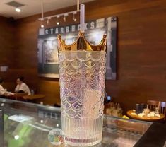 a glass with a gold crown on it sitting on a table in front of a restaurant