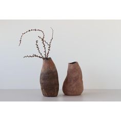 two vases with branches in them sitting on a table