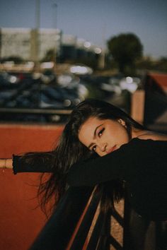 a woman leaning on a rail in front of a parking lot