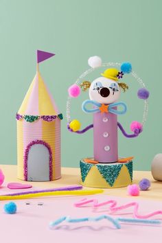 a paper doll is standing in front of a toy castle and other toys on the table