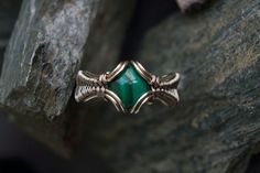 a green stone ring sitting on top of a tree branch