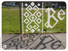 a fence with white letters on it behind a chain link fence in front of a grassy field