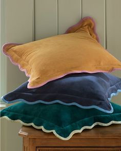 three pillows stacked on top of each other in front of a wooden cabinet and wall