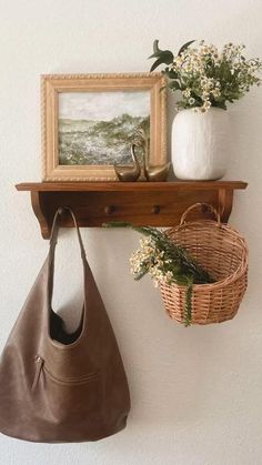 a brown purse is hanging on the wall next to a basket and vase with flowers