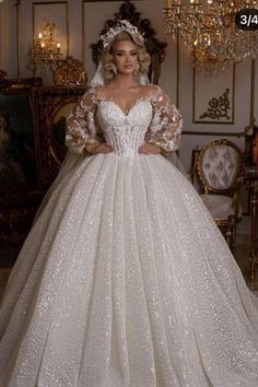 a woman in a wedding dress standing next to a chandelier with lights on it