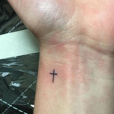 a small cross tattoo on the wrist