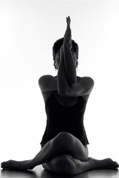 a woman sitting on the floor with her hands up in front of her face and arms stretched out