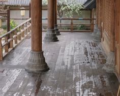 an empty porch with wooden pillars and lanterns