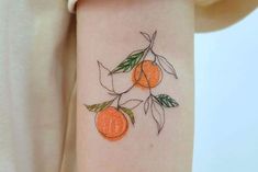 an orange tattoo on the arm with leaves and fruit drawn on it's side