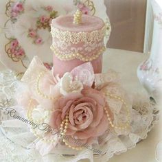 there is a pink cake with lace and flowers on the table next to other decorations