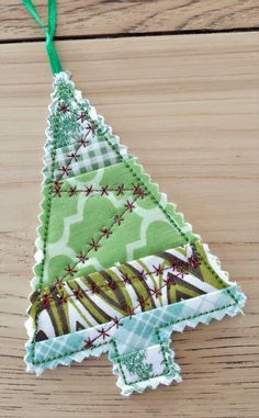 an ornament shaped like a christmas tree on a wooden table with green ribbon