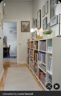 a long narrow hallway with bookshelves and pictures on the wall