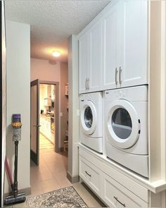 a washer and dryer in a room with white cabinets